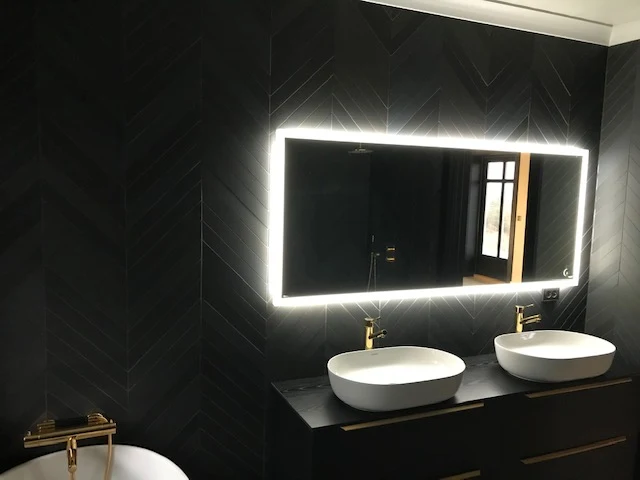 Sort bad med sorte overflater, hvit porselen, gull-detaljer og sorte fliser i fiskebeinsmønster