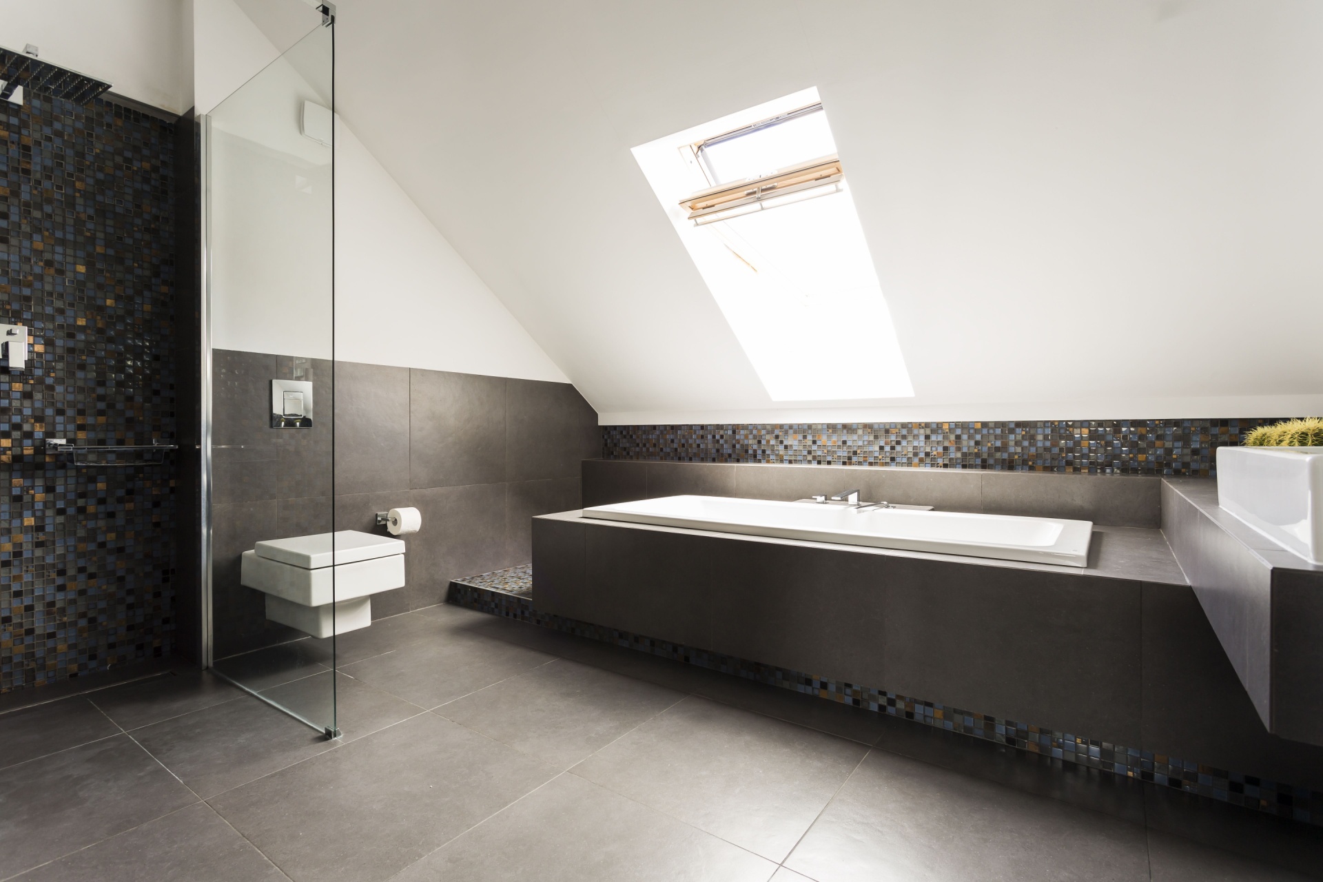 Moderne, stort bad med grå-, gull- og blåfarget veggfliser, grå gulvfliser, med dusj, badekar og WC